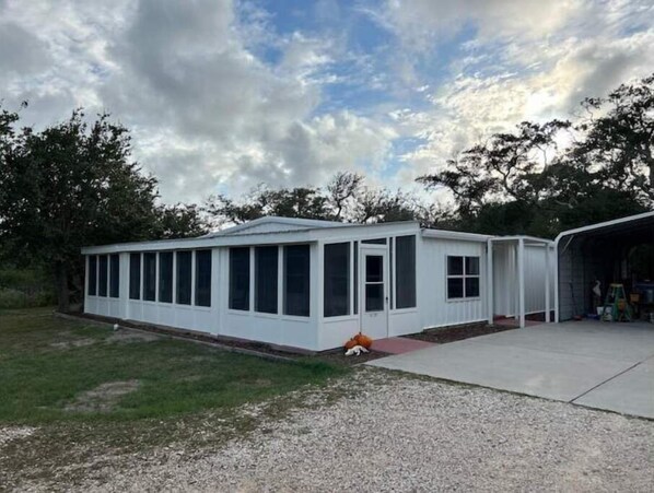 A single-story, white mobile home with a covered porch and a garage.