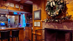 A cozy bar area with a fireplace, wooden bar counter, and seating.