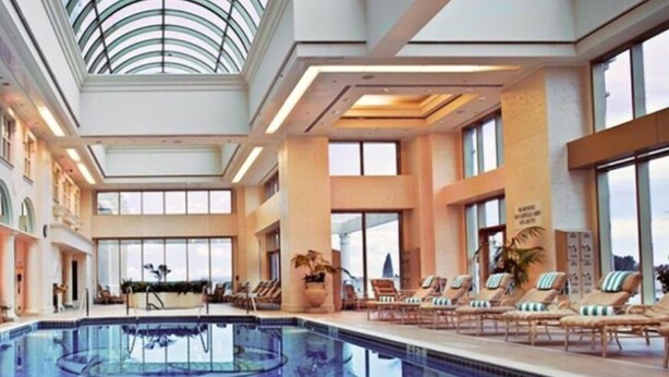An indoor swimming pool with lounge chairs and a skylight ceiling.
