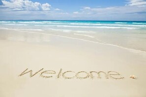 A beach with the word "Welcome" written in the sand.