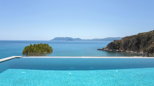 A clear blue pool with a view of the sea and distant islands.