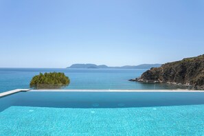 A clear blue pool with a view of the sea and distant islands. - SeaFront Villa With Private Beach & Swimming Pool (Vasilikos)