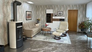 En moderne stue med en indbygget pejs, en sofa, en lænestol, et lille bord og en dekorativ vase.