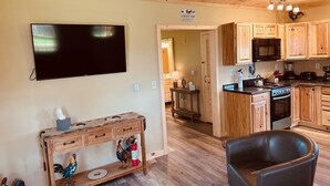 A wooden interior with a TV, wooden cabinets, a kitchen area, and a leather chair. - Cozy Cabin Boarding Winslow Hill Elk Viewing Area! (Benezette)