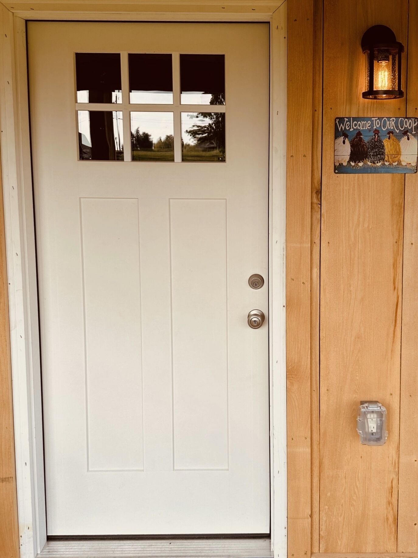 A white door with a small window and a doorbell.