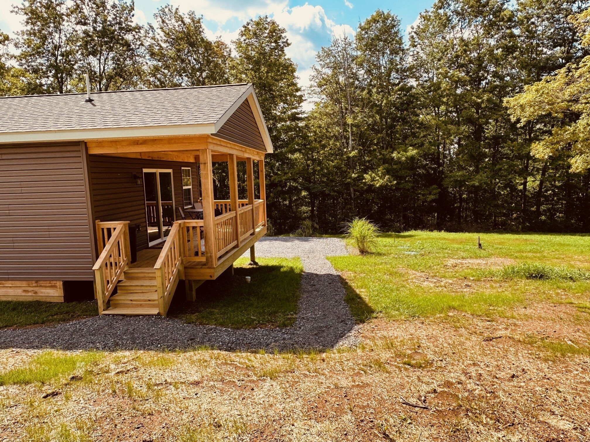 A wooden cabin with a porch and a gravel path leading to it.