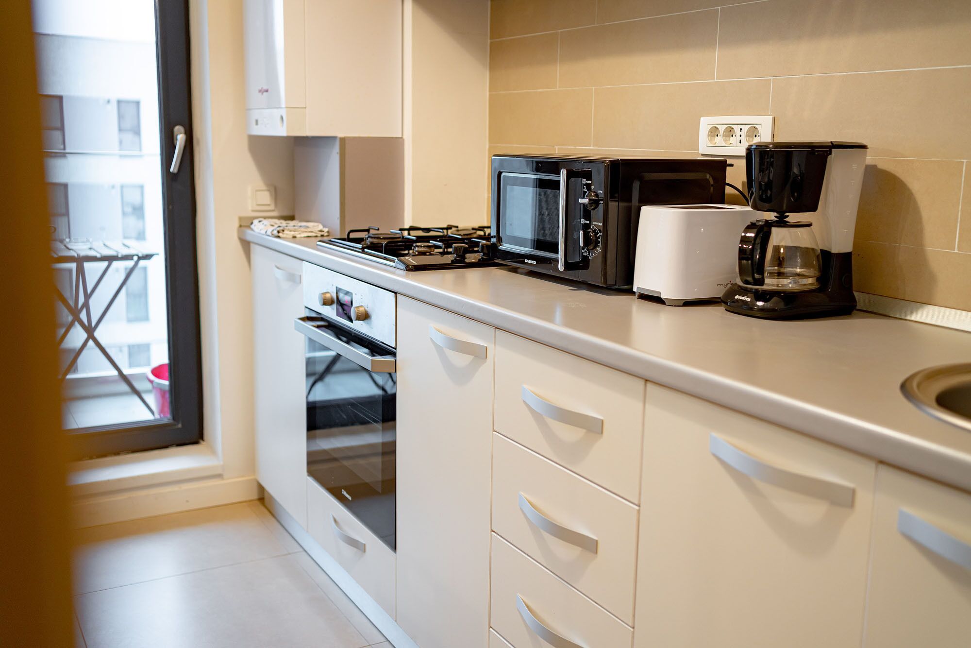 Una cocina moderna equipada con estufa a gas, microondas, tostadora y cafetera.