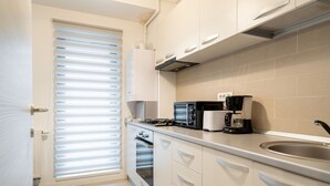 A modern kitchen with white cabinets, a built-in oven, a microwave, and a coffee maker. - Cozy spacious studio in new building (București)