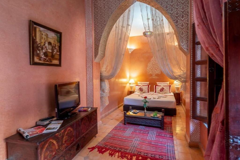 Une chambre à coucher comprenant un lit, un téléviseur, un meuble décoratif et une grande fenêtre donnant sur un beau paysage.