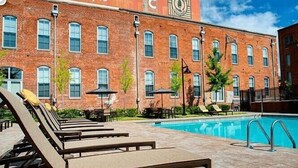 Un bâtiment en briques avec une piscine et des chaises longues.