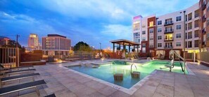 A hotel pool area with a hot tub, lounge chairs, and a covered seating area. - 100 Year Old Historic Brick 2BR Loft High Ceiling3 (Durham)