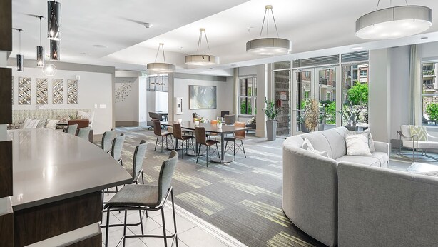 Una hall moderna di un hotel con zona ristoro, angolo salotto e ampie finestre con vista sulla città.