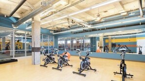 A gym with exercise bikes, a large mirror, and a wooden floor.