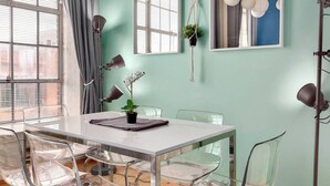 A modern dining area with a white table, clear chairs, and pendant lights. - 100 Year-Old Historic Brick 2BR Loft-High Ceiling8 (Durham)