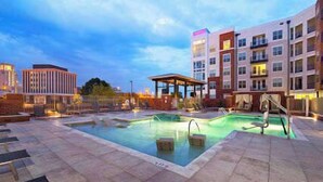 Un área de piscina de hotel con un jacuzzi, sillas de descanso y una zona de estar cubierta.