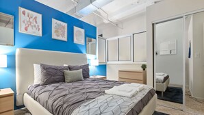 Un dormitorio moderno con una cama grande, mesitas de noche, un aparador y un vestidor.