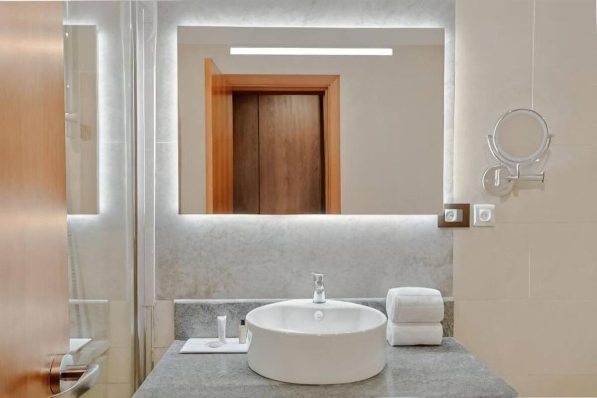Une salle de bain moderne avec un lavabo rond, un miroir et un porte-serviettes.