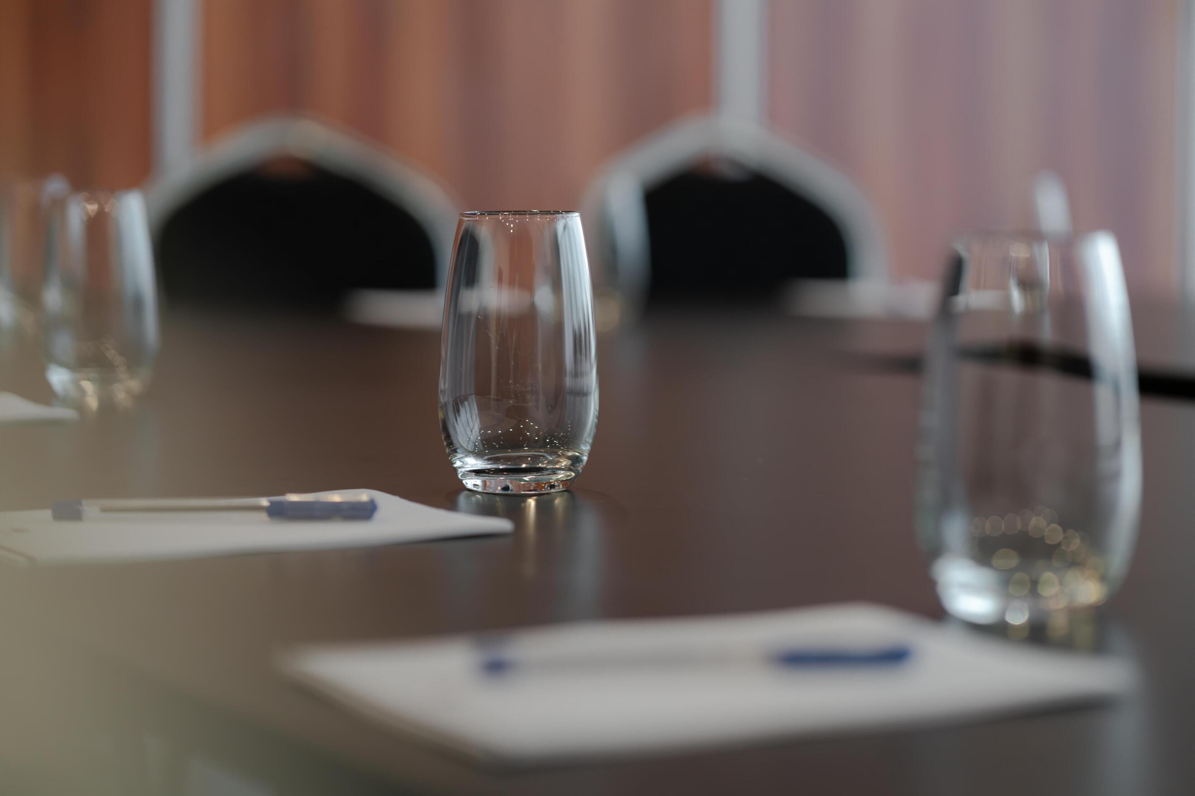 A conference table with empty glasses and a pen, indicating a meeting setup.