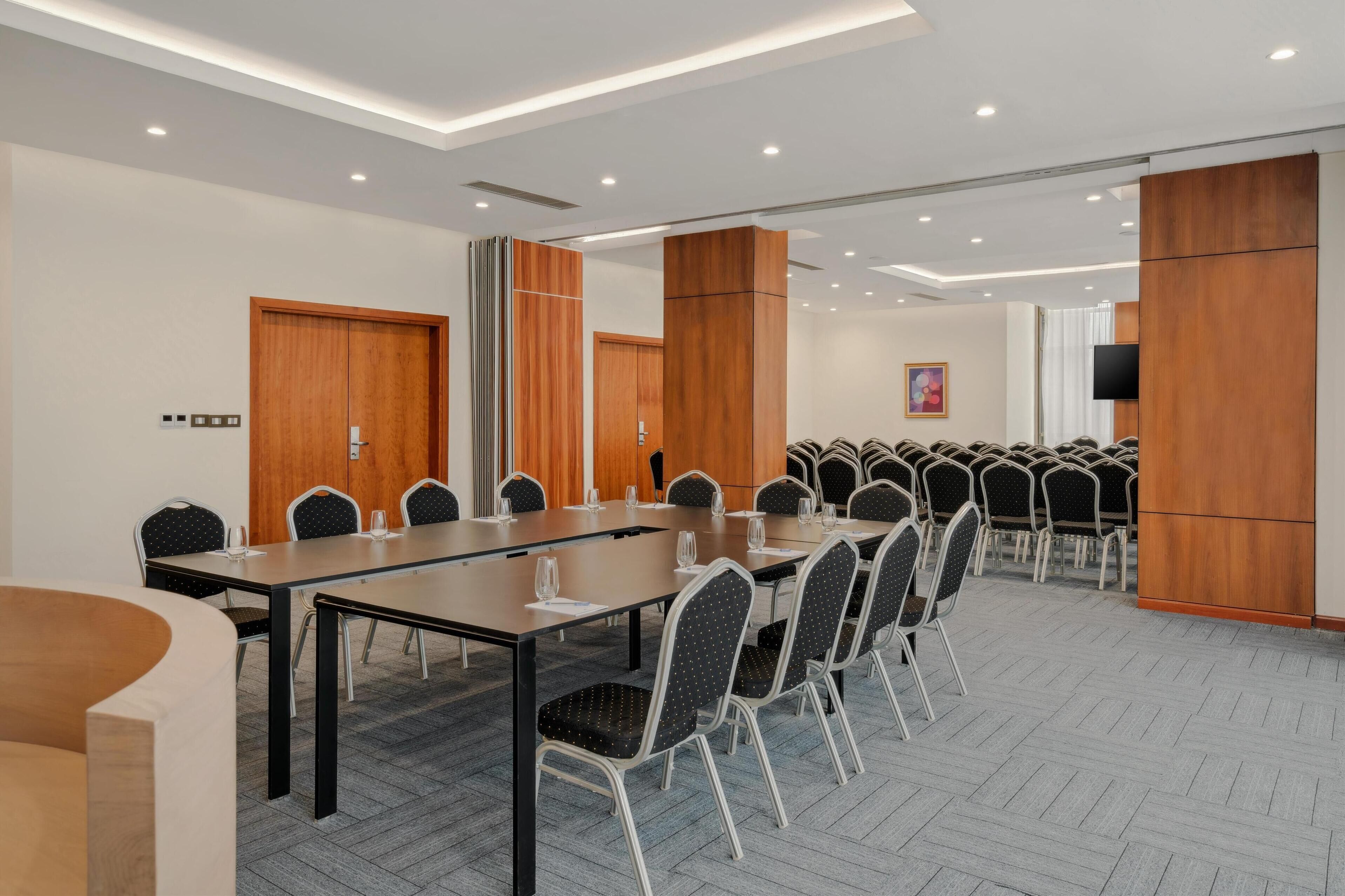 Une salle de conférence avec une longue table, des chaises et un téléviseur.