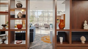 A modern interior with wooden shelving displaying decorative items, a central seating area with sofas, and a view through a glass partition to an outdoor space. - Doubletree By Hilton Addis Ababa Airport (Addis Ababa)