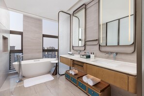 Een moderne badkamer met een vrijstaand bad, een grote spiegel en een wastafel met aanrecht.