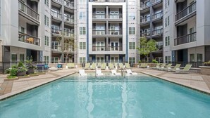 Un bâtiment moderne à plusieurs étages, doté d’une piscine centrale entourée de chaises longues.