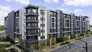 Un immeuble résidentiel à plusieurs étages, doté de balcons, d’une entrée au niveau du sol et donnant sur la rue.