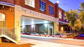 A brick building with a sign reading "WEST VILLAGE." - 100 Year-Old Historic Brick 2BR Loft -Large Patio1 (Durham)