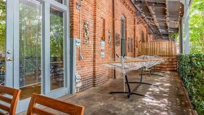 Un'area patio esterna con un muro in mattoni, una zona salotto coperta e un tavolo sotto un tendale.