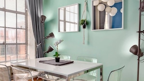 Un espace repas moderne avec une table blanche, des chaises transparentes et une plante suspendue.