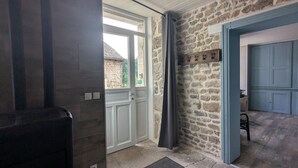 A stone-walled hallway with a white door, a blue door, and a small wooden shelf with hooks. - L'oustal du Lac, à Proximité du lac de Naussac et des Sentiers de Randonnée (Auroux)