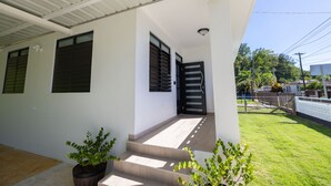 Una casa moderna con un porche cubierto, una escalera que conduce a una puerta y un pequeño jardín.