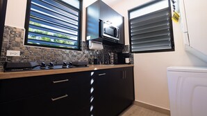 Una cocina moderna con armarios negros, un microondas y una cafetera.