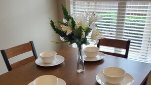 Une table à manger avec quatre bols blancs et un vase rempli de fleurs.