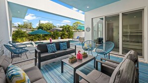 Un patio exterior con piscina, mobiliario y vistas a la vegetación circundante.