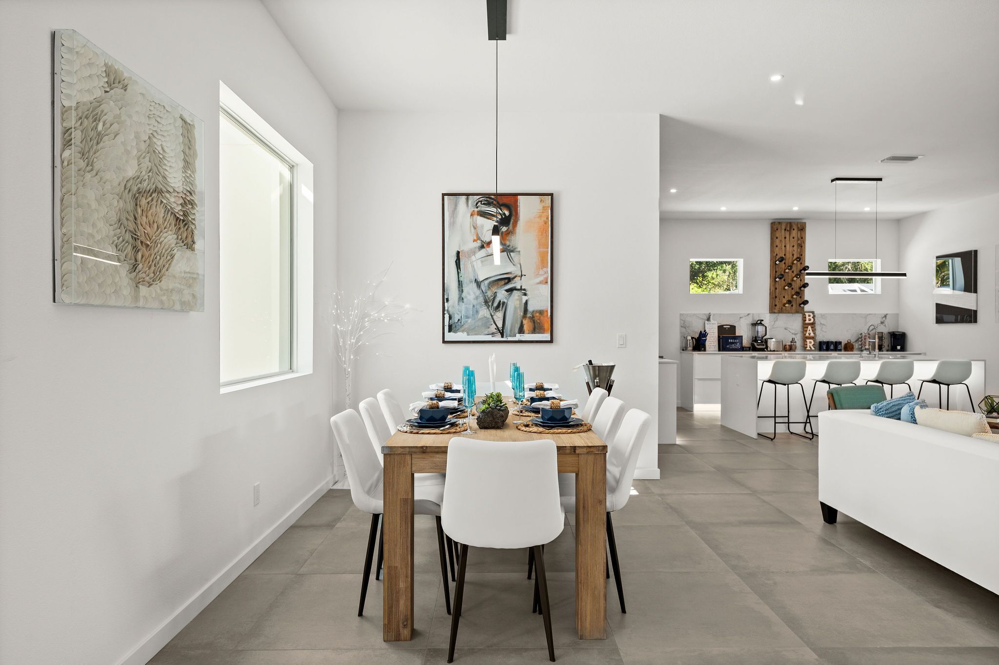 A modern dining area with a wooden table, white chairs, and a central art piece.