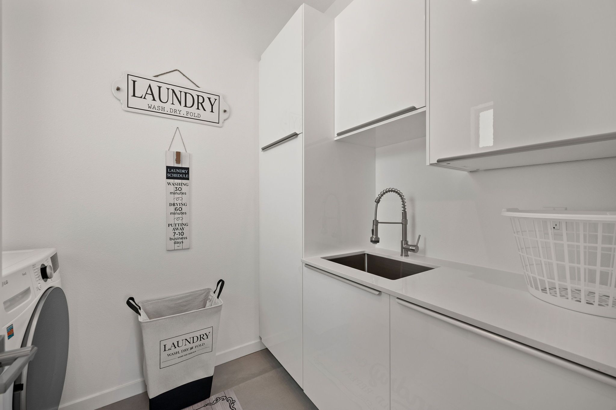 Een moderne keuken met een ingebouwde spoelbak, een wasstation en een witte wasmand.