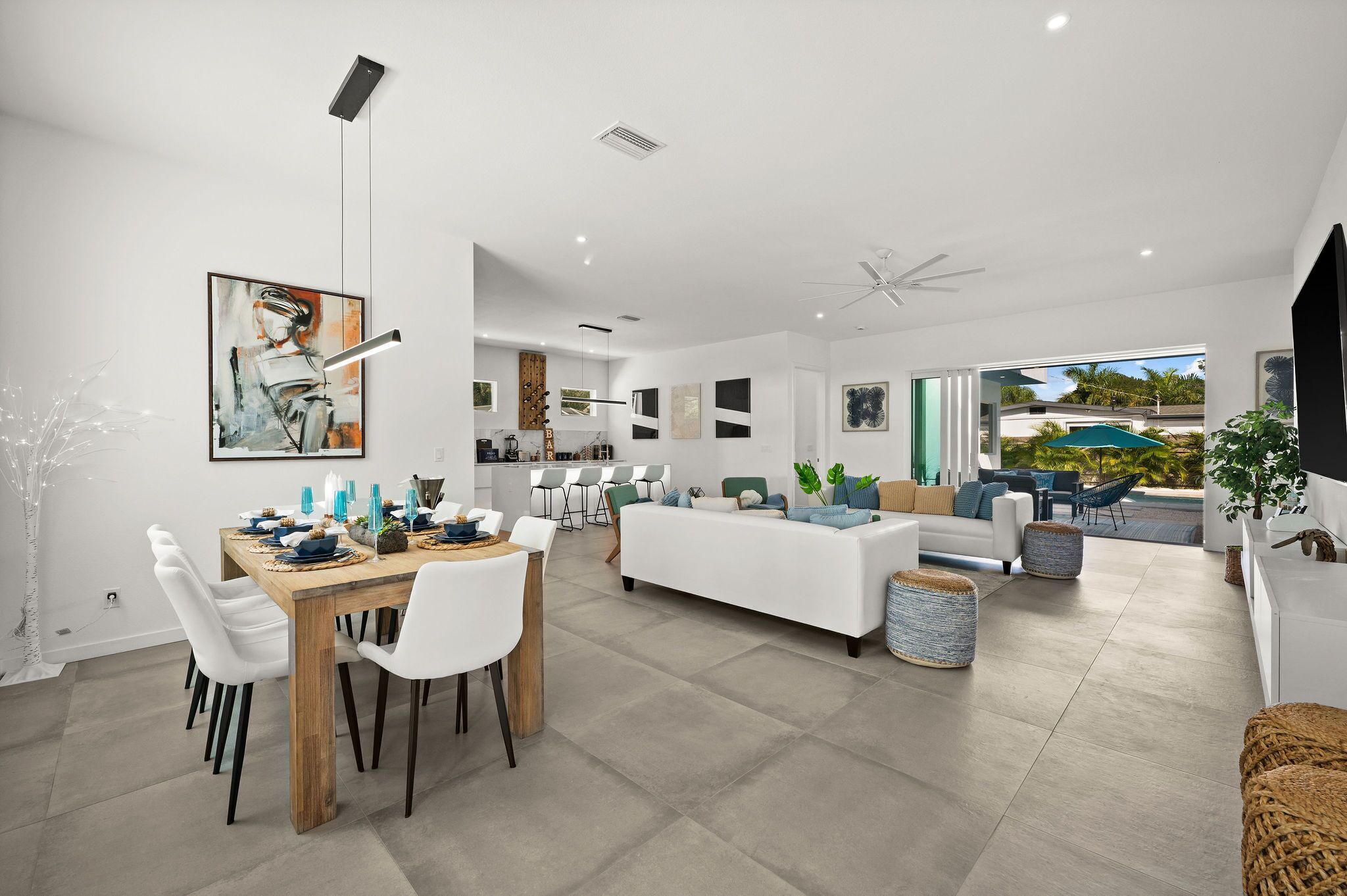 Un espacio habitable moderno y abierto con comedor, un sofá blanco y vistas al exterior.