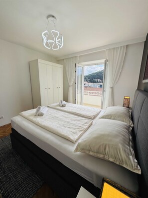 Un dormitorio con cama, armario, ventana con cortinas e iluminación en el techo.