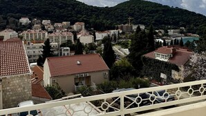 A residential area with buildings, a road, and a hill in the background. - KABLAR'S SUNNY SUITES 2BR apartment with balcony (Dubrovnik)