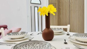 A dining table set with plates, cutlery, and a vase with yellow flowers. - KABLAR'S SUNNY SUITES 2BR apartment with balcony (Dubrovnik)