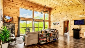 A spacious living room with a fireplace, large windows, a sofa, a coffee table, and a foosball table.