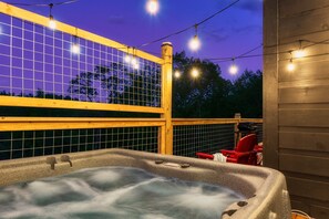 Un bain à remous avec une terrasse en bois, une clôture en bois et des guirlandes lumineuses.