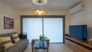 A modern living room with a sofa, a coffee table, a TV, and a large window. - Departamento Nuevo en la Mejor Zona de la Ciudad (Mendoza)