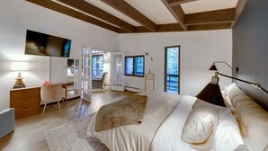 A bedroom with a large bed, a desk, a chair, and a wardrobe.