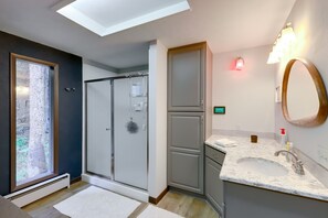 A modern bathroom with a skylight, a walk-in shower, a large mirror, and a marble sink. - Mid-Century Cabin: Creekside, Easy Access to i-70 (Dumont)