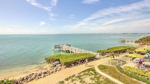 A beachside resort with a wooden pier, lounge chairs, and a walking path along the shore. - Classic & Comfortable Oceanfront Condo (Key Colony Beach)