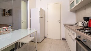 Una cocina compacta equipada con refrigerador, cafetera y estufa.