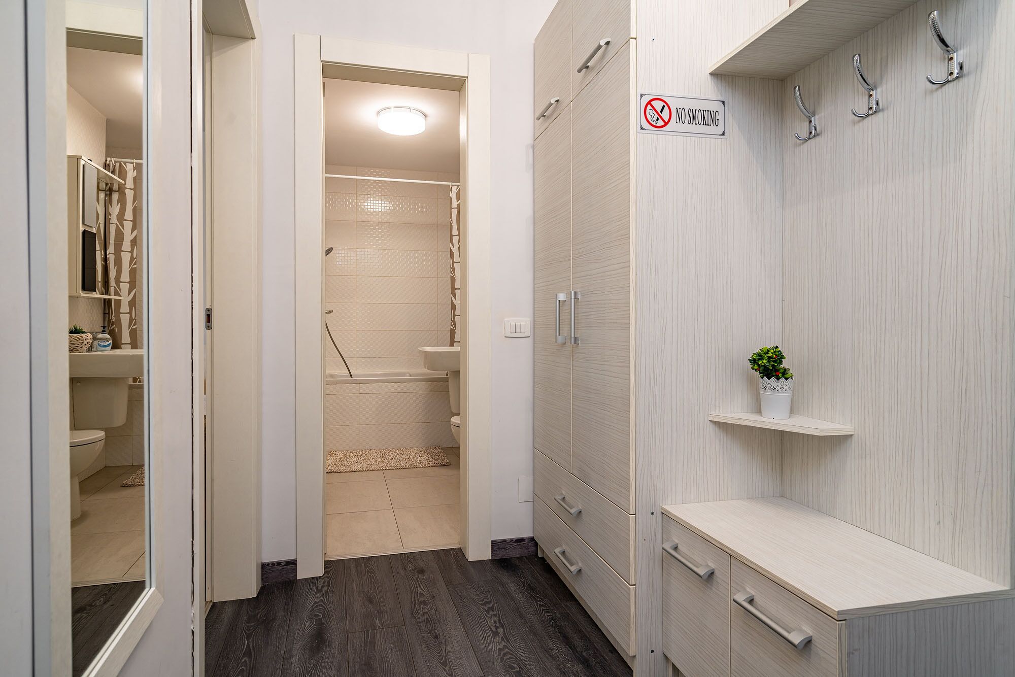 A bathroom with a shower, toilet, and sink. There is a 'No Smoking' sign on the wall.