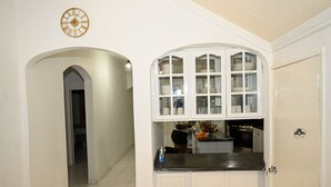 Een keuken met witte kastjes, een zwart aanrecht en een klok aan de muur.